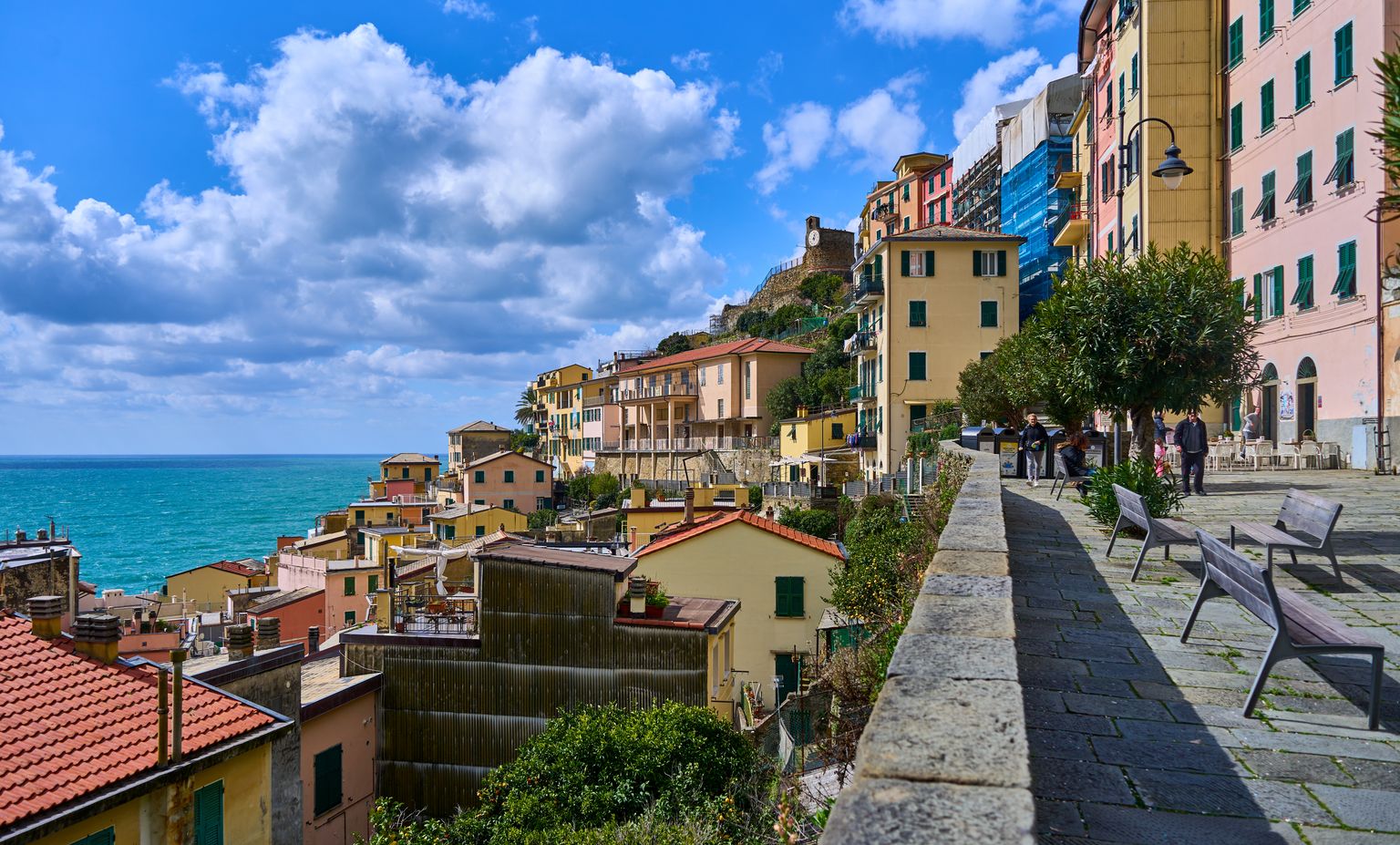 Colorful coastal houses in a charming Italian village by the sea under a vibrant sky.